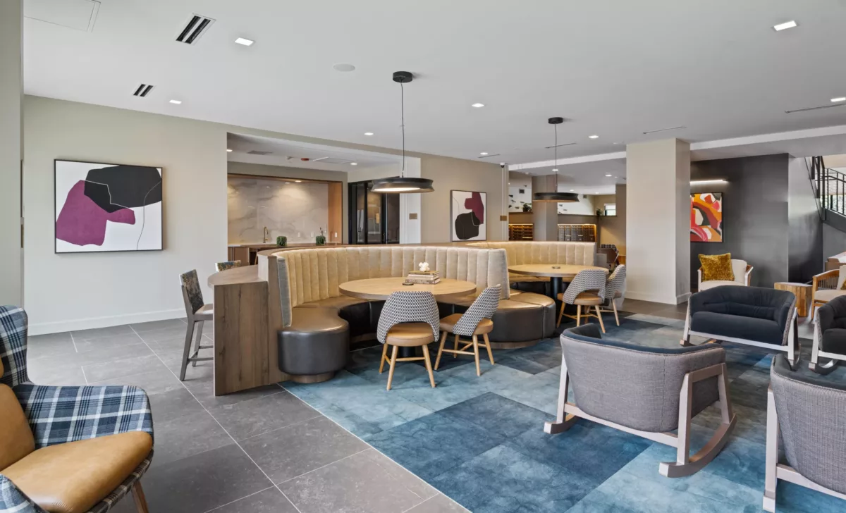 Casual seating area with booths, small round tables, chairs, and modern art on the walls.